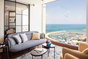 a living room with a couch and a view of the ocean at Renaissance Tel Aviv Hotel in Tel Aviv