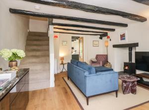 Old Farm Cottage في آمبيلسايد: غرفة معيشة مع أريكة زرقاء ودرج