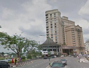 een groot gebouw aan een drukke stadsstraat met auto's bij Riverbank suites waterfront in Kuching