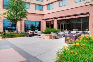 a building with a patio with tables and chairs at Sheraton McKinney in McKinney
