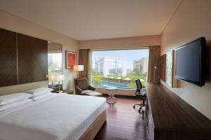 una camera d'albergo con un grande letto e una grande finestra di Courtyard by Marriott Mumbai International Airport a Mumbai