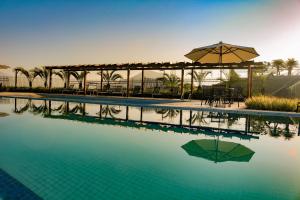 uma piscina com um guarda-sol, uma mesa e cadeiras em Apartamento Resort em Praia grande - Ubatuba em Ubatuba