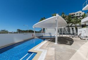 a swimming pool with an umbrella next to a building at Resort Apartment with Ocean Views in Maroochydore