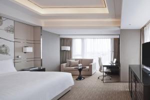 上海市にあるシャンハイ マリオット ホテル パークビューの大きなベッドとデスクが備わるホテルルームです。