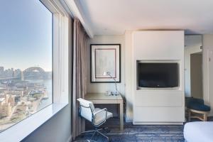Habitación de hotel con escritorio y ventana grande. en Sydney Harbour Marriott Hotel at Circular Quay en Sídney