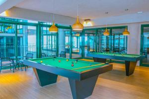 uma sala de bilhar com duas mesas de bilhar e janelas em Apartamento Resort em Praia grande - Ubatuba em Ubatuba