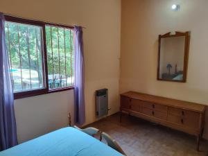 ein Schlafzimmer mit einem Bett, einem Spiegel und einer Kommode in der Unterkunft Cabañas Pequeño Paraíso in Tunuyán
