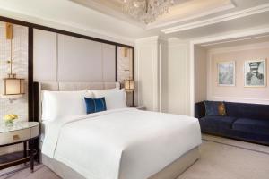雅加達的住宿－The St. Regis Jakarta，卧室配有白色的床和蓝色的沙发