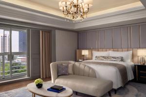 ein Schlafzimmer mit einem Bett, einem Stuhl und einem Tisch in der Unterkunft The St. Regis Jakarta in Jakarta