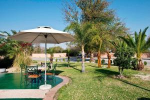 einen Tisch und Stühle mit einem Sonnenschirm neben einem Pool in der Unterkunft Protea Hotel by Marriott Ondangwa in Ondangwa