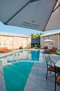 a pool at a hotel with chairs and an umbrella at Protea Hotel by Marriott Ondangwa in Ondangwa