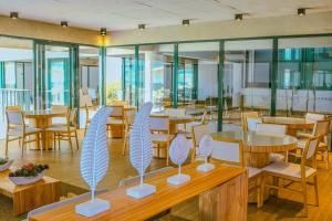um restaurante com mesas e cadeiras de madeira e janelas em Apartamento Resort em Praia grande - Ubatuba em Ubatuba