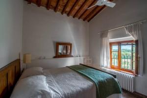 a white bedroom with a bed and a window at Appartamento con vista panoramica in Chianti in San Donnino