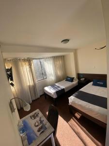 Habitación de hotel con 2 camas y mesa en Hotel Andenes, en Arequipa