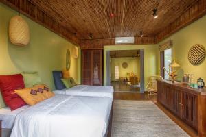 twee bedden in een kamer met groene muren en houten plafonds bij HỒ ĐÁ CỔ THIÊN LONG RESORT in Hòa Bình