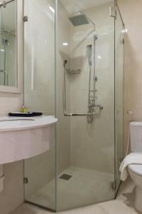 a glass shower in a bathroom with a sink and a toilet at The Pergola Design Hotel in Da Nang