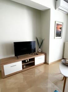 a living room with a flat screen tv on a wooden entertainment center at Beach House Holiday in Neoi Epivates