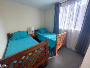 a small bedroom with two beds and a window at Departamento diario Copiapó in Copiapó