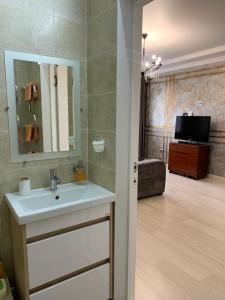 a bathroom with a sink and a television in a room at Апартаменты в районе Болашак in Aktobe