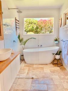 a white bathroom with a tub and a window at Laurant's Cottage ~ McLaren Vale entertainer in McLaren Vale