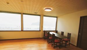 a dining room with a table and chairs and large windows at Uhome Kamogawa 本館-【ペット可/広い2LDK】 in Kamogawa
