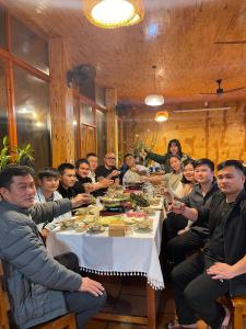 un grupo de personas sentadas alrededor de una mesa en Min's Ha Giang Hostel, en Ha Giang