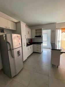 uma cozinha com armários brancos e um frigorífico em Apartamento en Coveñas cerca al mar #204 em Coveñas
