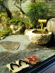 的住宿－夕食プランあり 一棟貸し民宿 春名，坐在喷泉旁的岩石上,一双拖鞋