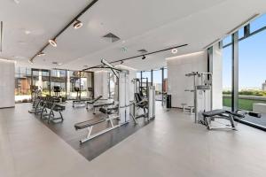 a gym with cardio equipment in a building with windows at City View Luxury 3 Bedroom Apartment-Free Car Park in Melbourne