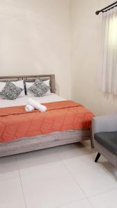 1 dormitorio con 1 cama con sábanas de color naranja y silla en Surokarsan 9 House Yogyakarta en Yogyakarta