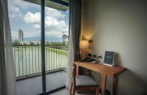 a desk in a room with a balcony with a window at Brique Suite in Chiang Mai