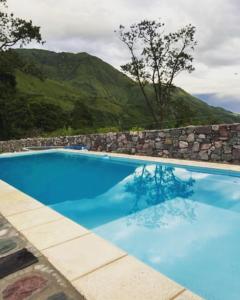 a large blue swimming pool with a stone wall at Santuyoc Lodge in Volcán