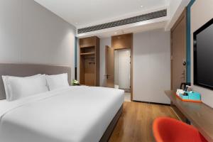 a bedroom with a white bed and a red chair at Holiday Inn Express Nanning Convention&Exhibition in Nanning