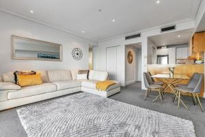 a living room with a white couch and a table at Sunset Harbour Sanctuary + CP in Auckland