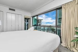 a large white bedroom with a large window at Sunset Harbour Sanctuary + CP in Auckland