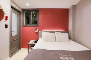 首爾的住宿－Hotel dongyangjang Dongdaemun-Jongno，一间卧室设有一张床和红色的墙壁