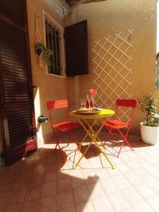 a yellow table and two red chairs on a patio at Baciati dal Sole-Self check-in in San Pellegrino Terme