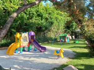 Dionyssos Village في كاتو داراتسو: حديقة مع ملعب مع زحليقة