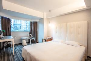 um quarto de hotel com uma cama, uma secretária e uma janela em Hotel Cloud Riverside em Tamsui