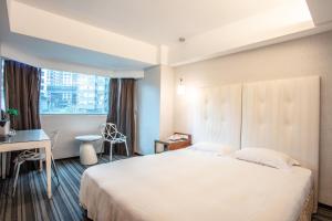 a hotel room with a bed and a desk and a window at Hotel Cloud Riverside in Tamsui