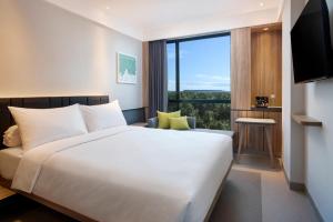 a hotel room with a bed and a large window at ibis Yogyakarta International Airport Kulon Progo in Yogyakarta
