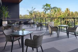 a patio with tables and chairs and palm trees at ibis Yogyakarta International Airport Kulon Progo in Yogyakarta