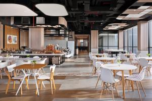 a restaurant with white tables and white chairs at ibis Yogyakarta International Airport Kulon Progo in Yogyakarta