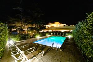 uma piscina à noite com cadeiras e um edifício em Villa La Collina di Montegrappa em Tuglie