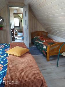 un dormitorio en el ático con 2 camas y un pasillo en Agroturystyka Giże - domek letni en Ełk