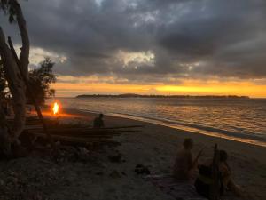 a group of people sitting on the beach at sunset at La Bohème in Gili Air
