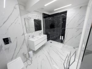 Baño blanco con lavabo y espejo en White Elegance Luxury B&B Caserta en Caserta