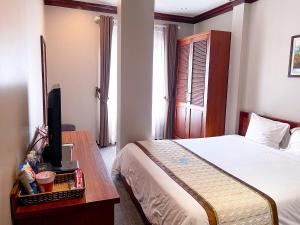 - une chambre avec un lit et un bureau avec une télévision dans l'établissement Nam Dat Hotel, à Hạ Long