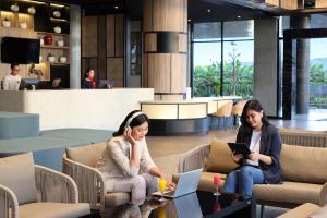 two women sitting in chairs in a lobby at ibis Yogyakarta International Airport Kulon Progo in Yogyakarta