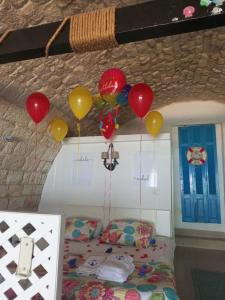 a room with a bed with balloons on the ceiling at Le Blanc Bleu in Jbeil